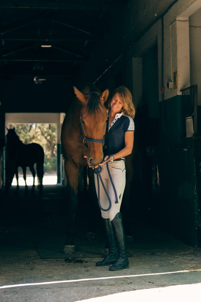 Happy equestrian with horse in barn