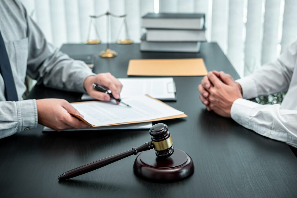 Male lawyer discussing negotiation legal case with client meeting with document contact in courtroom