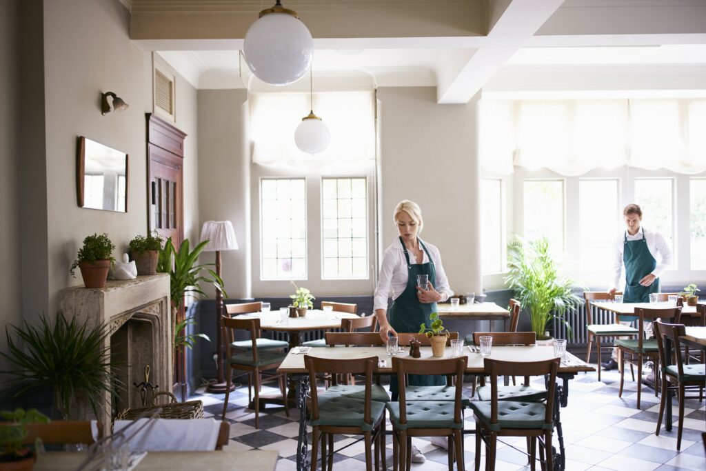 Staff Laying Tables In Empty Restaurant